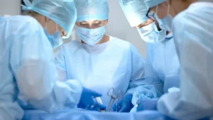 A group of surgeons in blue scrubs collaborates on a surgical procedure involving a patient on the operating table.